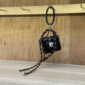 Black mini bag keychain with 8-ball charm and woven rope strap on wooden wall - Square Black Woven Mini Bag