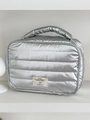 Detailed view of silver puffer makeup bag featuring horizontal quilting and woven label - Silver