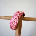 Detail of fuchsia and beige woven raffia headband with top knot on a wooden stand - Rose Red Series Knotted