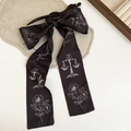 Macro di una clip per capelli vintage nera con fiocco e nastri stampati con bilancia e fiori - Forcina - Nero - Fiocco con Nastro Stampato