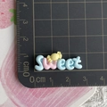 Dettaglio macro dello charm in resina 'Sweet' con motivo di caramelle su righello - Dolce / Blu Sweet