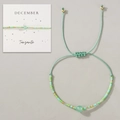 Verstellbares grünes Perlenarmband mit Steinperle auf einer Dezember-Karte - Dezember Geschenkbox/Grün