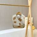 Waterproof baby bib with cute teddy bear pattern and front pocket on a wooden hanger - Bear