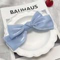 Light blue bow hair clip with pearlescent fabric on a white decorative plate - Ice Cream Blue