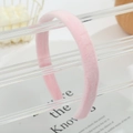 Close-up of soft pink velvet headband displayed on a modern acrylic stand with soft focus - Pink