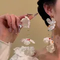 Detailed macro view of long white silk petal earrings with colorful transparent beads - Fabric 3D Floral Style (16#)