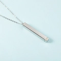 Close-up of a silver stainless steel vertical bar necklace on a light blue background - Steel