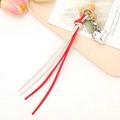 Red and white heart-shaped braided leather keychain with tassels on a pink plate - White + Red