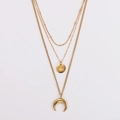 Detail of layered gold necklaces featuring starburst and crescent moon pendants - Gold
