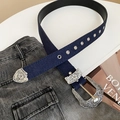 Détail d'une ceinture en denim bleu avec boucle florale baroque et œillets métalliques - Style boucle ciselée vintage / Bleu clair