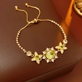 Detail of vintage gold bracelet with green round gemstone and floral accents on leather - Bracelet-Green