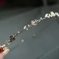 Elegante cerchietto in lega dorata con fiori di metallo, perle bianche e strass brillanti - Storia Di Rose Strass