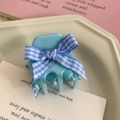 Dettaglio molletta per capelli azzurra con fiocco floreale su vassoio in ceramica - Blu