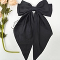 Detail view of large black satin bow hair clip with elegant long ribbon tassels on white - Black