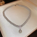 Detail van grijze parelketting met zirkoon druppelhanger in een beige sieradendoos - Grijs