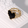 Detail eines verstellbaren Goldrings mit schwarzem Herz-Inlay auf weißem Reliefelement - Schwarz
