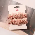 Close-up of pleated satin scrunchies in peach pink and champagne gold on display card - Ivory and Champagne