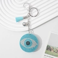 Blue rhinestone evil eye keychain with tassel, silver bell, and lobster clasp on white background - Lake Blue