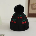 Detail of black winter knit hat featuring red cherry jacquard and soft faux fur pom-pom - 1-3 Years / Black