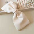 Detalle de un gran pasador de lazo en tela crema con un elegante collar de perlas - crema