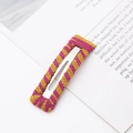 Dettaglio di un fermaglio per capelli in maglia a righe rosa e gialle su un libro - Rettangolare / Viola e Giallo