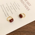 Eleganti orecchini quadrati dorati con pietra rossa su sfondo di carta vintage poetica - Borgogna