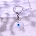 Blue and white evil eye charm keychain with silver metal ring on minimal background - White
