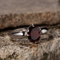 Macro shot of an oval red garnet set in a polished silver ring on a natural rock background - Natural Garnet Vintage Ring LR314