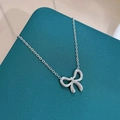 Macro-opname van zilveren strik hanger ketting op getextureerde blauwe sieradendoos - Zilveren Ketting