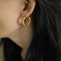 Mujer con pendientes de aro dorados con diseño geométrico de espiral retorcida - Dorado (EH18)