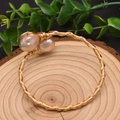 Gold metal woven bracelet with irregular pink pearls on a rustic wood base - Gold Large Baroque Pearl Style