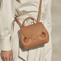 Polished caramel leather handbag with curved flap and textured pleats on a model - No Gift Box / Camel / Small