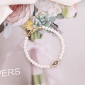 Detailaufnahme eines Perlenarmbands mit goldenem Hamsa-Hand-Anhänger auf Seide - Lila