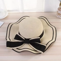 Close-up of wide brim straw sun hat featuring black ribbon bow and wavy edge trim - Wave Edge Black Bow Straw Hat Beige