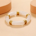 Minimalist acrylic tube bracelet with gold spacers on a warm beige background - Semi-Transparent White / Gold