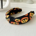 Détail d'un serre-tête d'Halloween noué avec des motifs citrouilles sur tissu noir - Bandeau Tête De Mort Citrouille Dorée