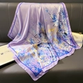 Elegante paarse zijden sjaal met gele en blauwe bloemmotieven op een leren bank - Paars