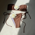 Detail of chocolate brown bikini set featuring large 3D white rose accents and side ties - Coffee