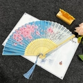 Blue folding fan with pink cherry blossoms, carved bamboo ribs, and a blue tassel - Cherry Blossom Dance - Pink Blue
