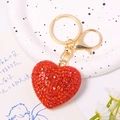 Detail of red heart crystal keychain with gold metal clasp on decorative porcelain plate - Red Quicksand Texture Heart