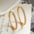 Elegante vergoldete ovale Creolen mit Zirkonia-Besatz vor Vintage-Papierhintergrund - Ovaler Reif / Gold