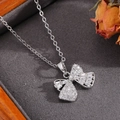 Close-up of a silver bow necklace with white zircon pavé on dark textured fabric - Silver Square Diamond Splicing Bowknot Necklace