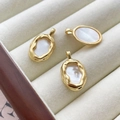 Close-up of three 14k gold-filled oval shell pendants with hammered texture on a tray - 18K Gold Plated Border White Shell