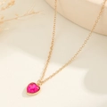 Dettaglio di una collana a cuore dorata con ciondolo in pietra rosa su base materica - Rosa Rosso