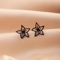 Macro shot of black hollow flower earrings on champagne silk fabric with fine metal details - Black