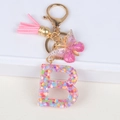 Detail showing pink sequin letter B keychain with leather tassel and butterfly charm - Letter B
