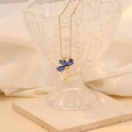 Detail van een gouden ketting met een blauwe bloemhanger op een kristallen schaal - 4# Koningsblauw