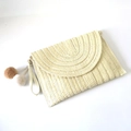 Detail der cremefarbenen Clutch mit halbkreisförmiger Webstruktur und Plüschbommeln - Gebrochenes Weiß