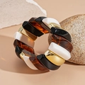 Detail of chunky acrylic cuff featuring black, amber, and gold geometric resin blocks - Colorful