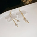 Detalle de pendientes de pétalos blancos con perlas y tallos dorados en un plato blanco - Gancho de oreja de pétalo blanco